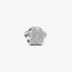 A silver four-petal flower charm with a textured pavé-like finish, shown on a plain light gray background.