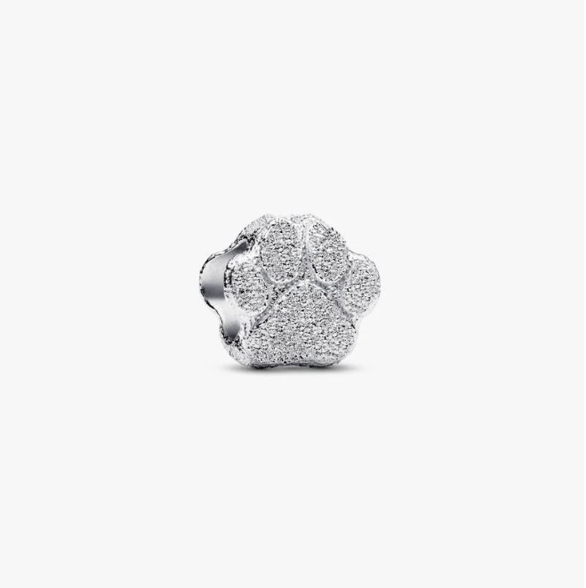 A silver four-petal flower charm with a textured pavé-like finish, shown on a plain light gray background.