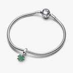 Silver bracelet with a green heart charm on a white background