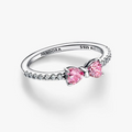 A Pandora ring featuring two pink heart-shaped gemstones on a silver band with small clear stones, shown on a clean white background.