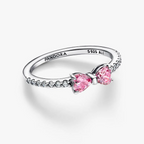 A Pandora ring featuring two pink heart-shaped gemstones on a silver band with small clear stones, shown on a clean white background.