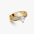 A Pandora gold ring featuring a heart-shaped clear gemstone in a prong setting, with pavé-set accent stones along the split shank, shown on a clean white background.