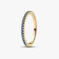 A slim yellow gold eternity ring featuring a continuous row of round-cut blue sapphires, shown on a clean light gray background. The brand name 'PANCO' is engraved on the inside of the band.