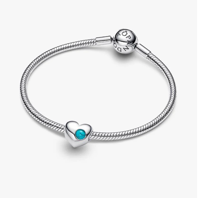 A silver snake-braided bracelet with a heart charm featuring a small turquoise blue stone, displayed on a clean light gray background.