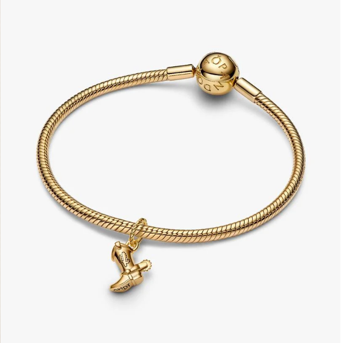A gold-plated snake chain bracelet with a small flying bird charm and a round bead clasp, shown on a light gray background.