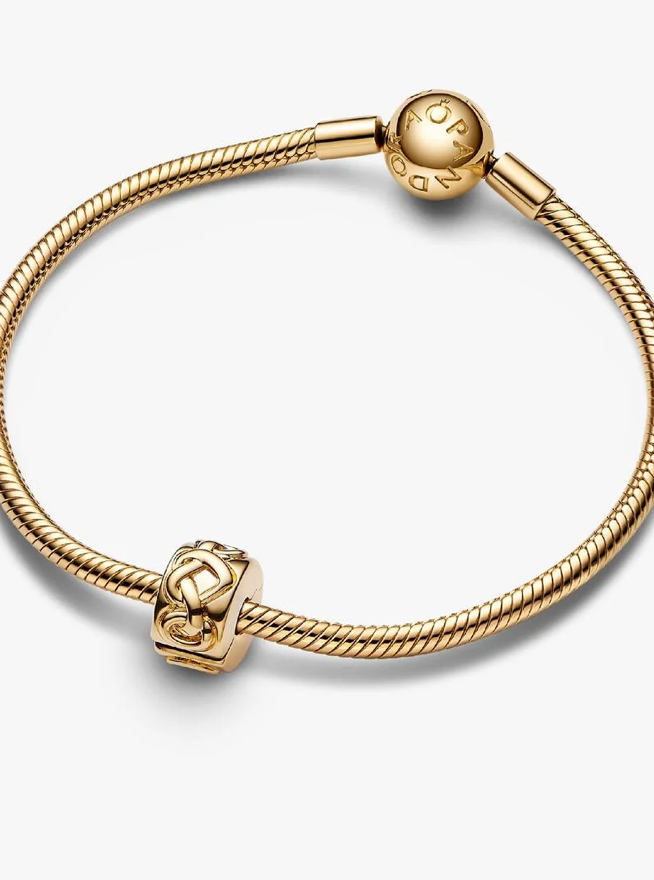 A gold-plated snake chain bracelet with a round charm engraved with 'PANDORA' and a decorative cube charm, shown on a light gray background.
