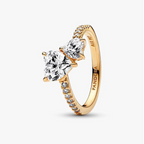 A gold ring with three heart-shaped clear gemstones and small accent stones along the band, shown on a clean white background. The brand name 'PANDORA' is engraved inside the band.