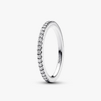 A silver eternity ring with a row of small clear stones, shown on a clean white background. The brand name 'PANDORA' is engraved inside the band.