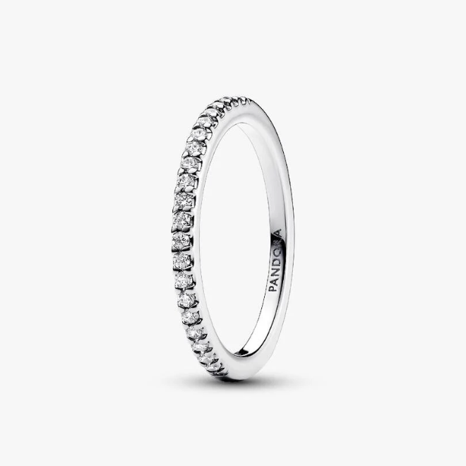 A silver eternity ring with a row of small clear stones, shown on a clean white background. The brand name 'PANDORA' is engraved inside the band.